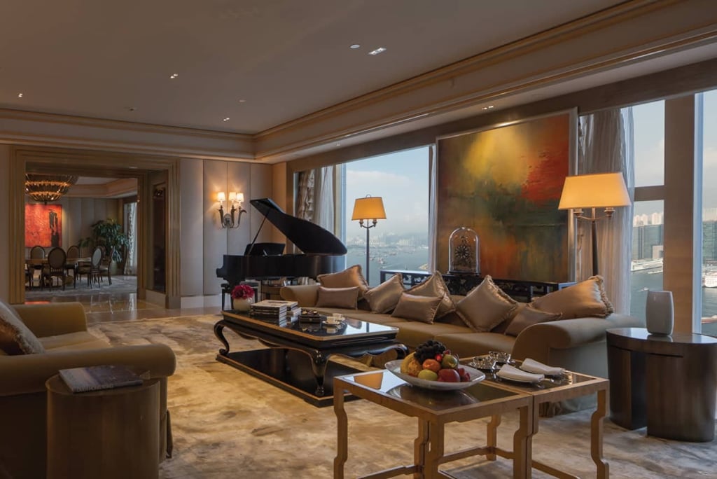 Luxury hotel suite with elegant furniture, grand piano, and city view.