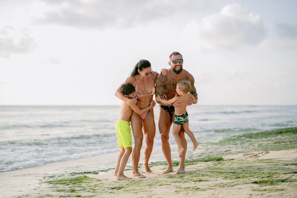 Family sharing a warm embrace on the shoreline rocks during a family photo session at Dreamland Beach Bali.