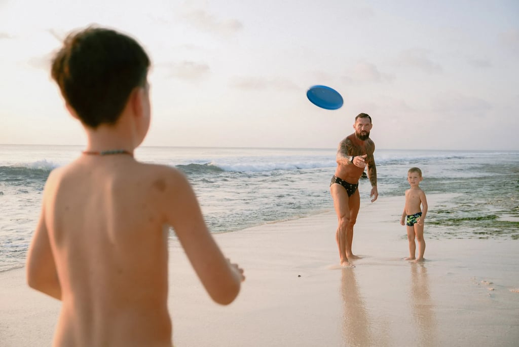 Young boy playing frisbee on the beach during a relaxed family photography session at Dreamland Beach Bali.