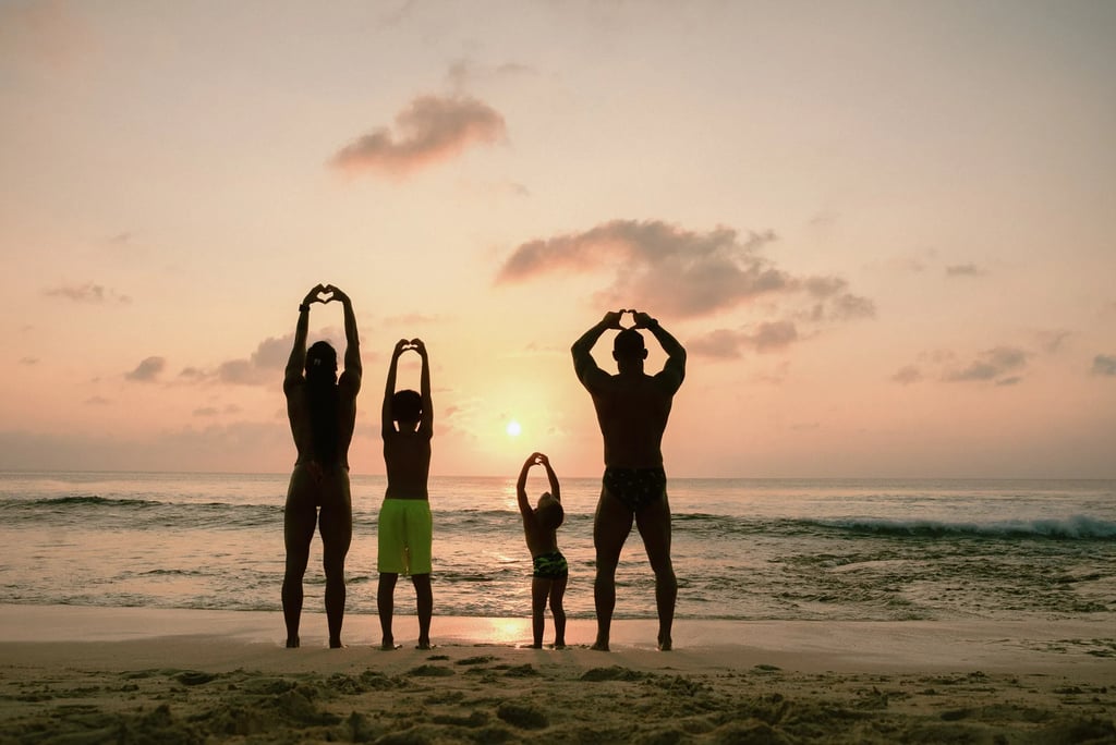 Family standing together at sunset on Dreamland Beach Bali enjoying an oceanfront family photography session.