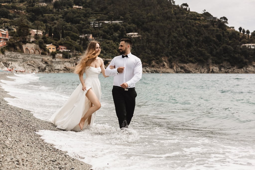 a man and woman walking along a beach in Bonassola