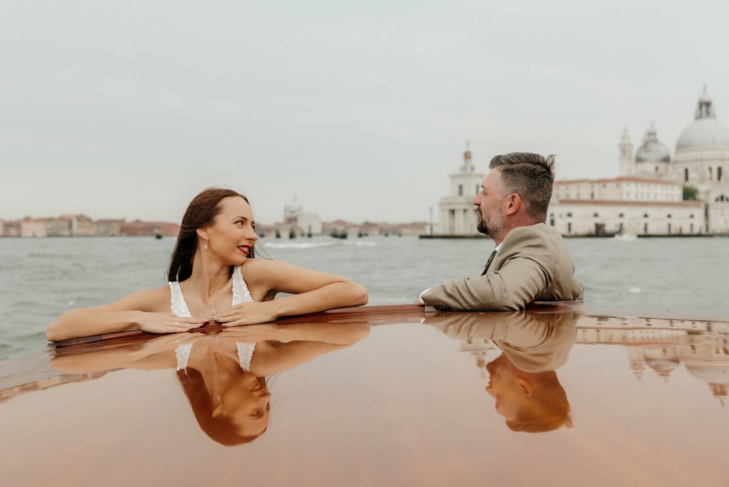 a man and woman sitting on a taxi boat in venice wedding