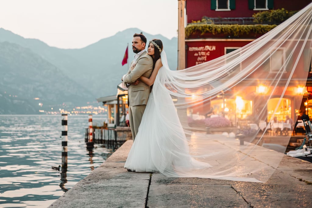 a bride and groom standing on a pier in Malcesine