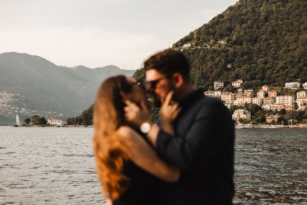 a man and woman kissing in front of a mountain
