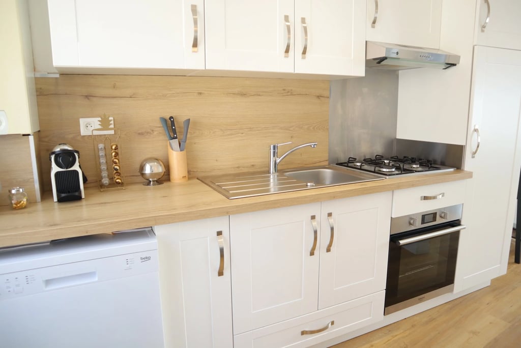 Cuisine équipée moderne avec four, plaques, lave-vaisselle et plan de travail en bois