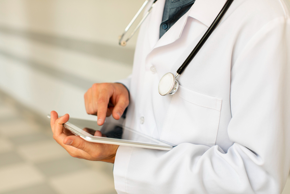 A doctor in a white lab coat using a digital tablet for healthcare data and patient records.