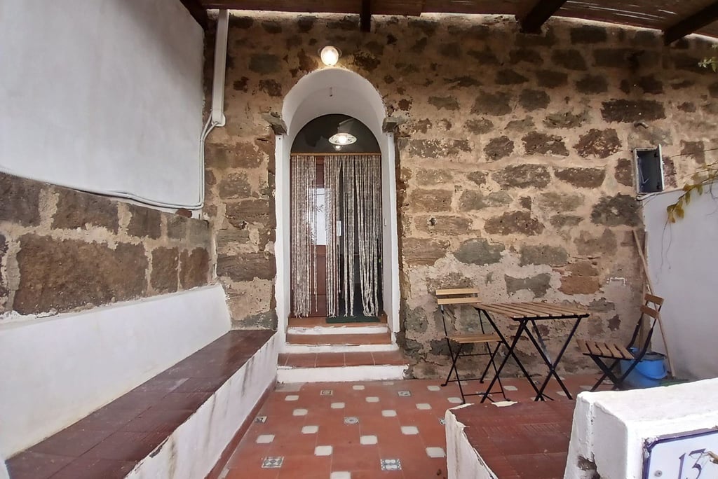 Entrance of a dammuso in Rekhale with stone arch, beaded curtain and tiled patio