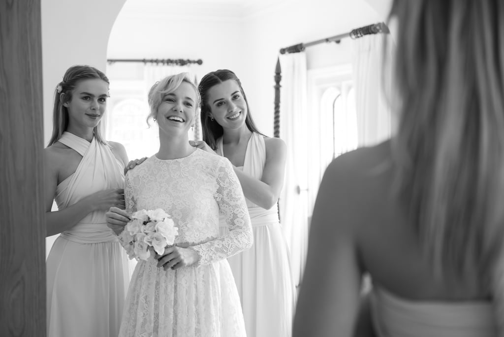 black & white reflection photo of bride and bridesmaids, looking in the mirror laughing and having a good time