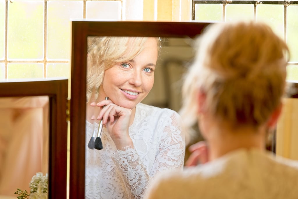 bride's reflection in the mirror looking into the camera lens with a big smile on her face
