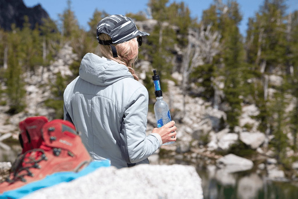 Hiker using Sawyer Mini Water Filter while hiking in the Rockies