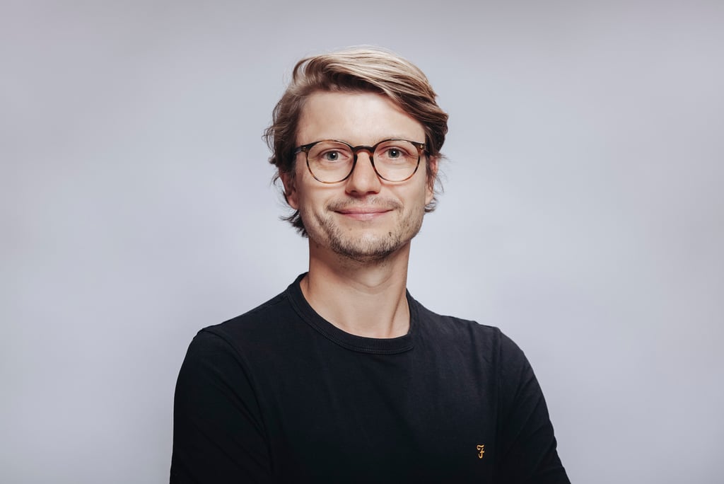 Junger Mann in einem schwarzen T-Shirt, fotografiert in einem Studio.