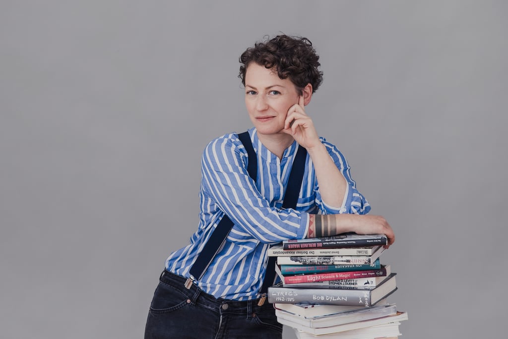 A woman in a stripped shirt leaning on a stack of books.