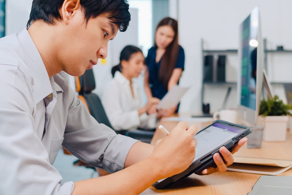 a man sitting at a table with a tablet and a woman standing next to him