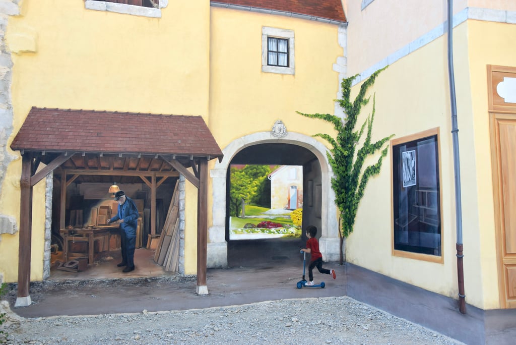Détails d'une fresque en trompe-l'oeil peinte sur une façade, Un atelier, un enfant en trottinette.