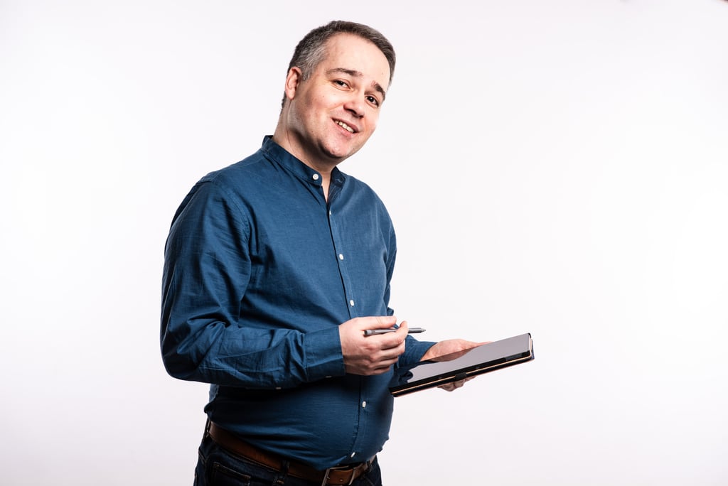 Conseiller immobilier avec une tablette. Il porte une chemise bleue.