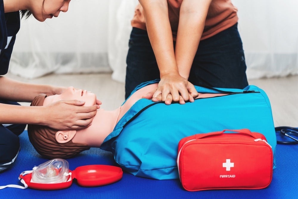 Two people practising CPR on a dummy in First Aid training