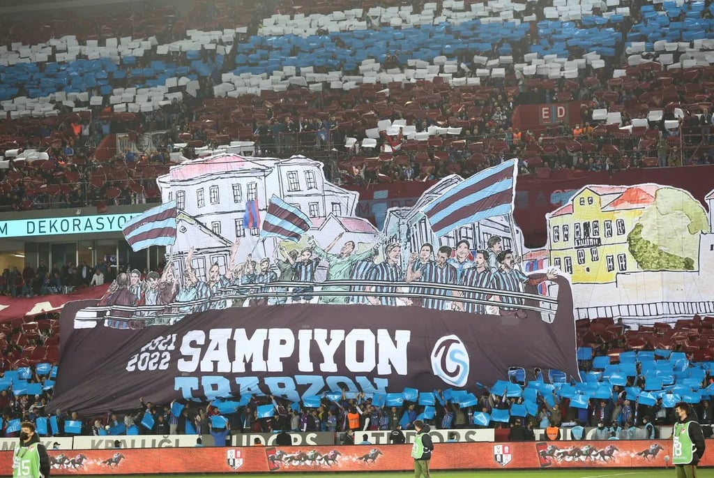 Ultras von Trabzonspor im Stadion mit Fahnen, Fackeln und intensiver Stimmung während eines Spiels in Trabzon.