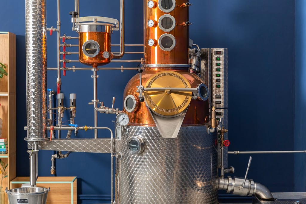 foto di un alambicco in rame e acciaio con tante tubature su sfondo blu