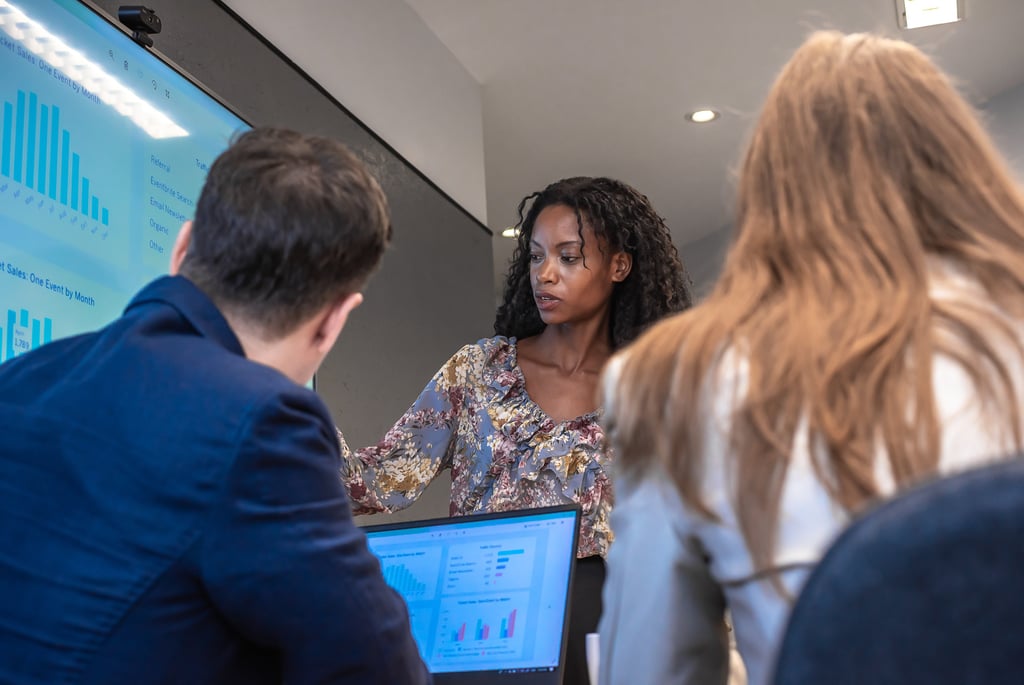 Woman presenting data on a screen to colleagues during a meeting.