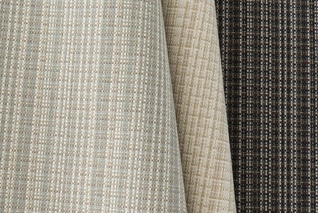 Textured woven upholstery fabric samples in neutral shades of beige, grey, and charcoal.