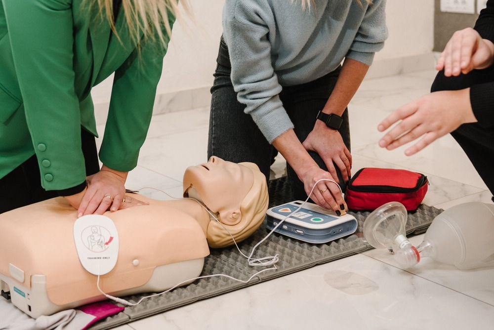 Two women administering CPR training on a CPR dummy in a training