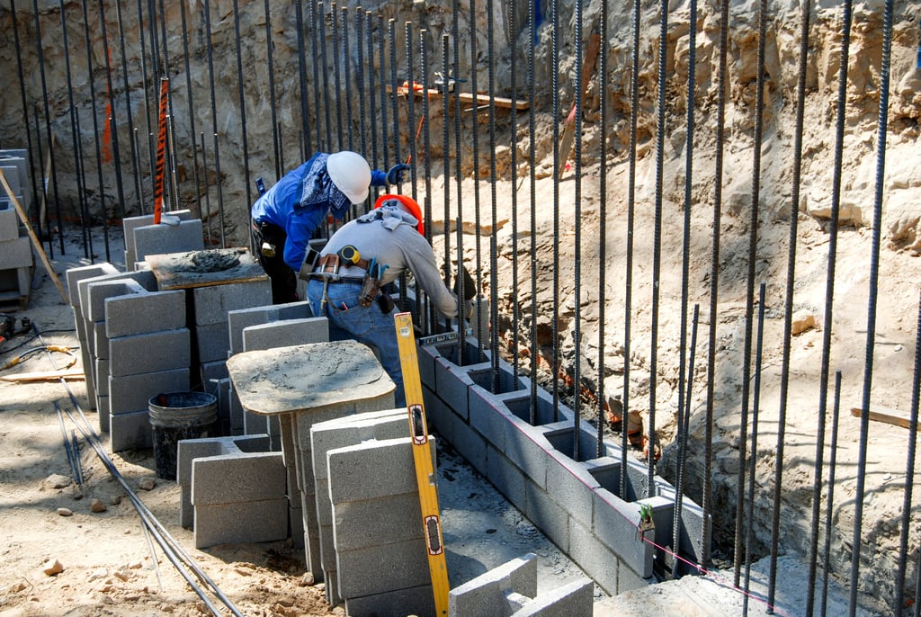 Concrete retaining wall installation with reinforced block construction