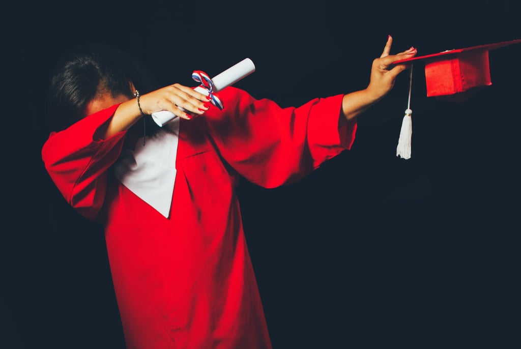 Indian student in red graduation gown celebrating academic success, holding a diploma and tassel