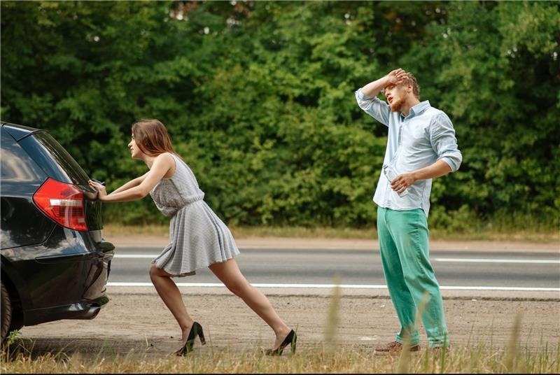 the man watches as the woman pushes the car