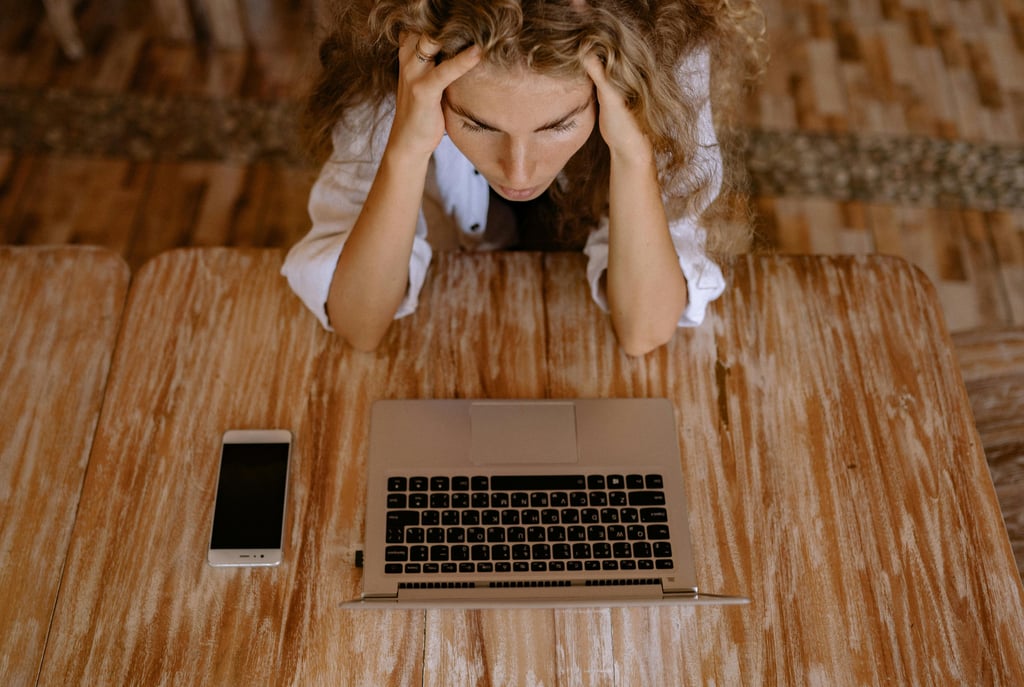 a woman sitting at a table with a laptop and a cell phone