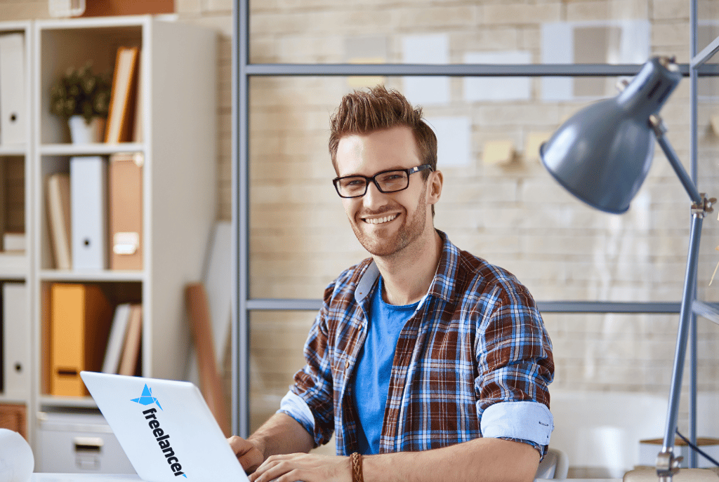 a man sitting at a desk with a laptop computer freelancing