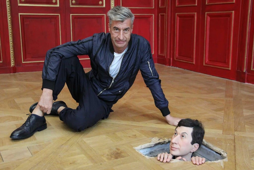 Maurizio Cattelan posando à beira de “Little Cattelan from Rotterdam” (2010) durante a exposição