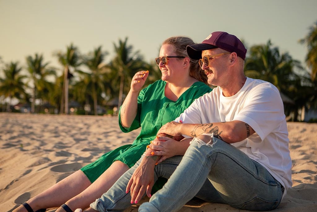 Couple sitting together on the beach during a family photoshoot at Mövenpick Resort Phu Quoc