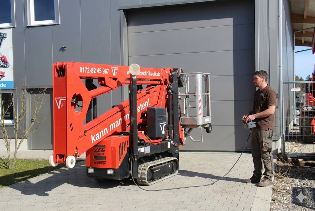 Schreinermeister Ferdinand Volk steuert die rote Raupen-Arbeitsbühne per Kabelfernbedienung vor seiner Werkhalle am Ammersee.