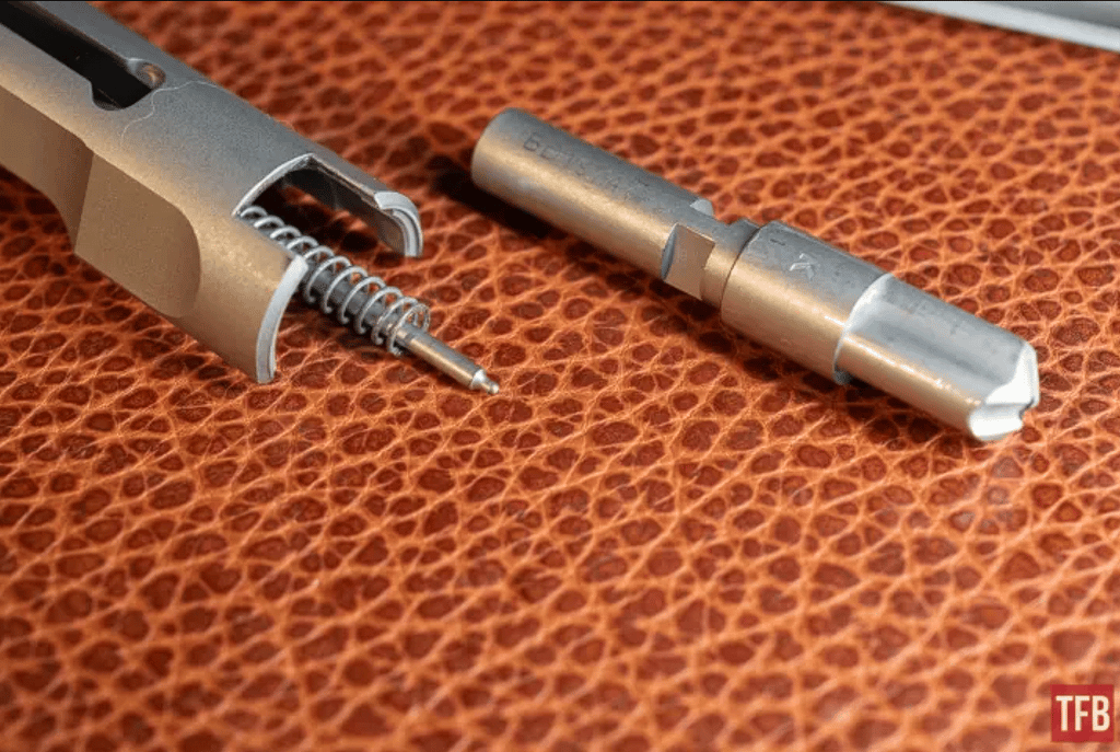 Zerlegter Mean Arms Bearing Delayed Verschluss mit eingesetztem Schlagbolzen und Steuerstück daneben