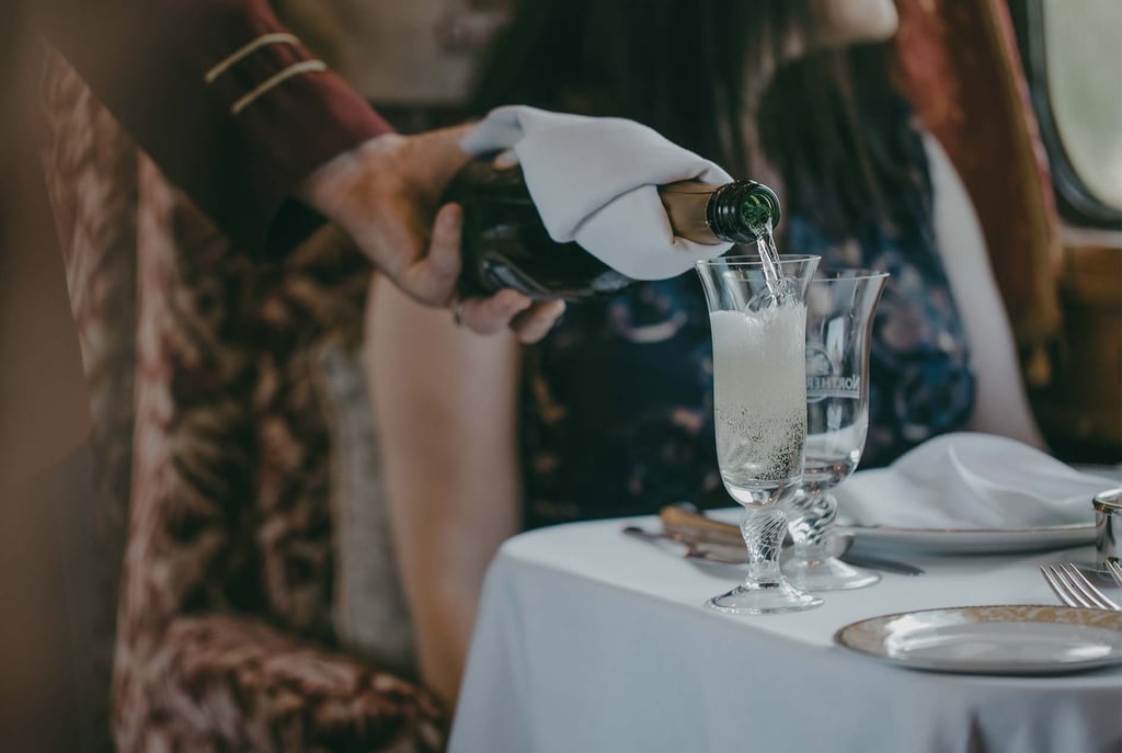 Champagne being poured onboard the Northern Belle luxury train dining experience.
