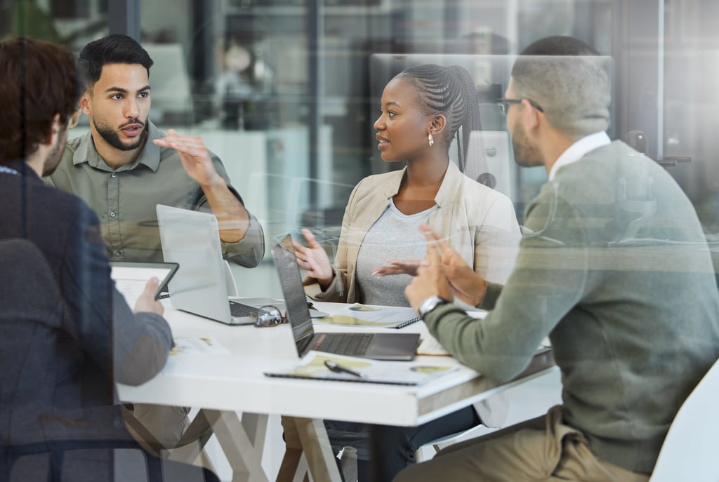 Team in a meeting discussing work around a table at a tech company