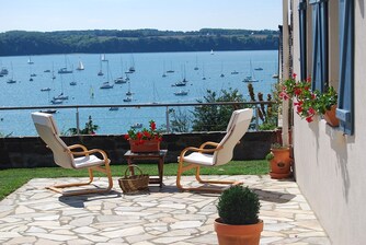 Sunny stone patio with lounge chairs overlooking a bay filled with sailboats and yachts.