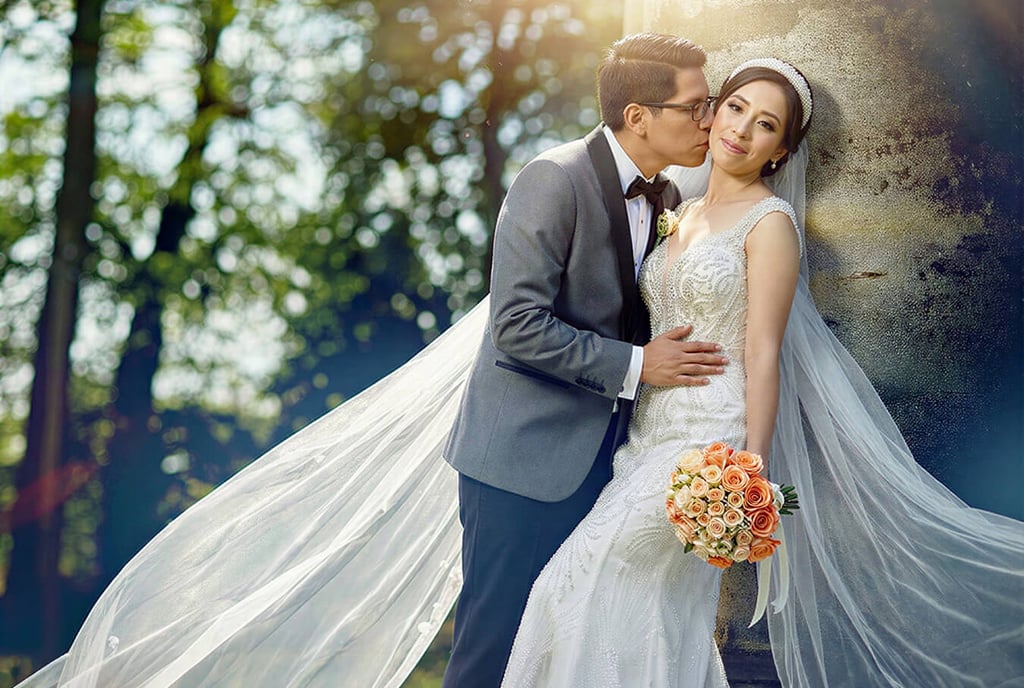 Novio besando a la novia boliviana al aire libre. Ella con vestido sirena y velo largo.