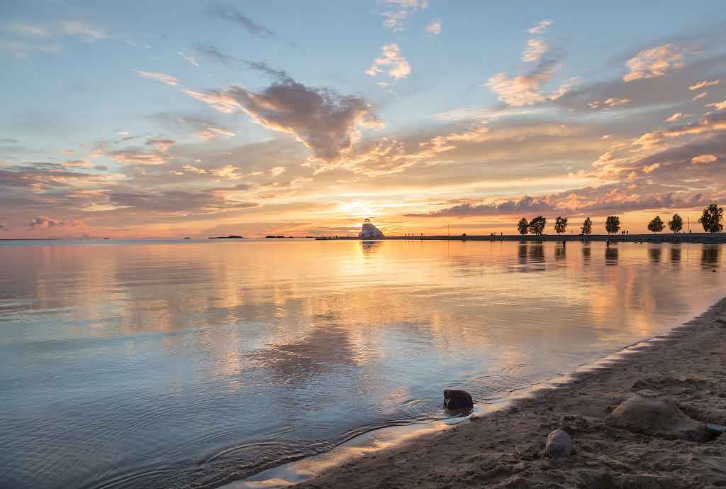 Sunset over a calm beach in Oulu, reflecting summer and winter swimming opportunities along the Both