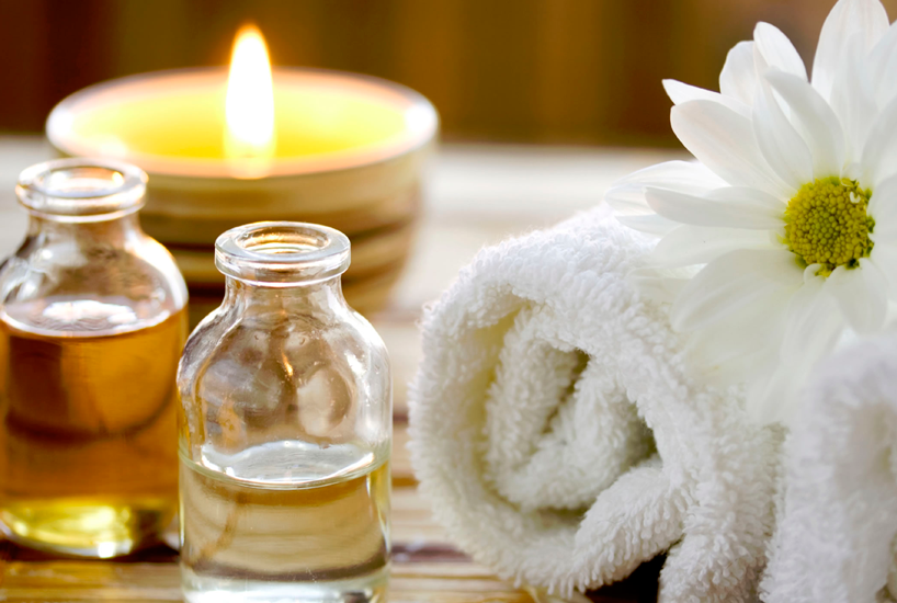 oleos para massagem, vela, toalha e uma flor