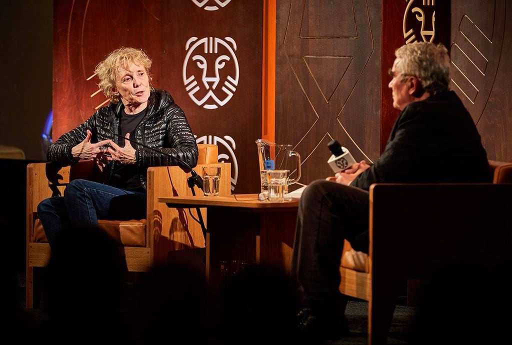 French director Claire Denis speaking at a film festival stage interview with a moderator.