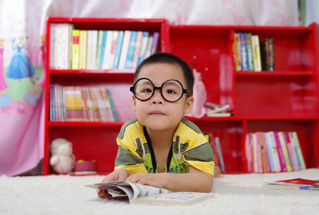 imagem de um menino de seis anos deitado num tapete lendo um livro
