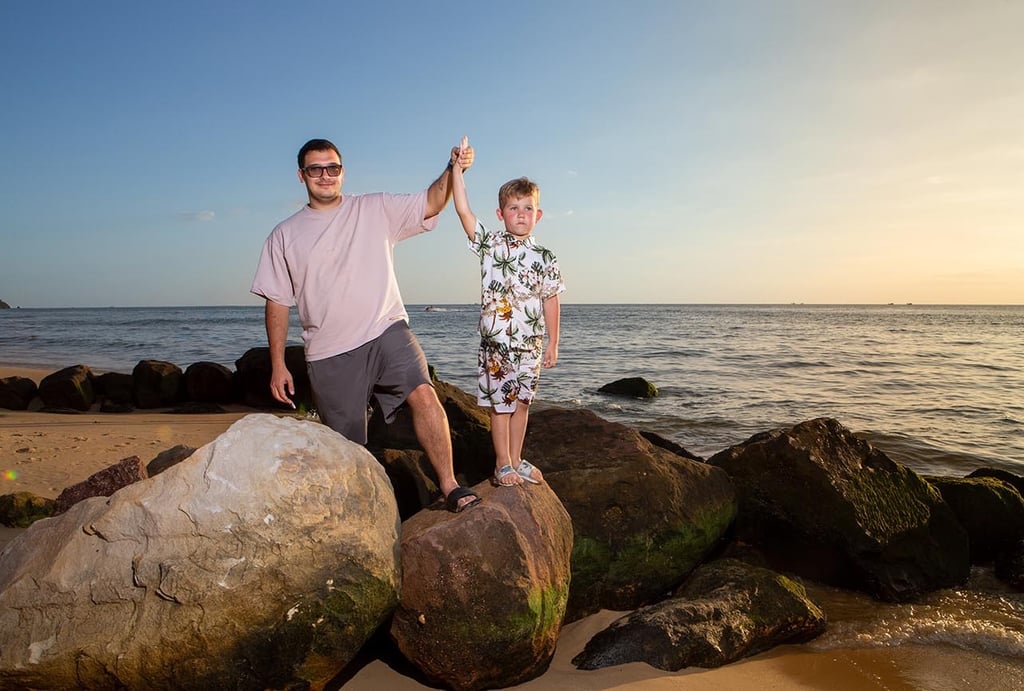 Папа и сын стоят на камнях на пляже Radisson Blu Resort