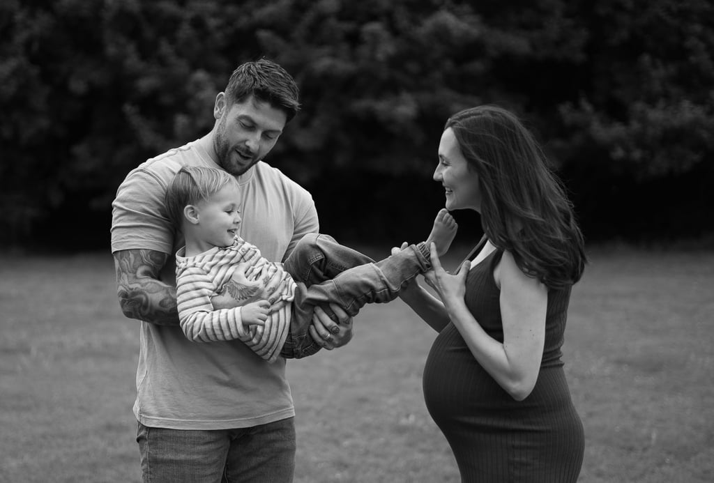 Black and white image with father holding his son and mother tickling his feet