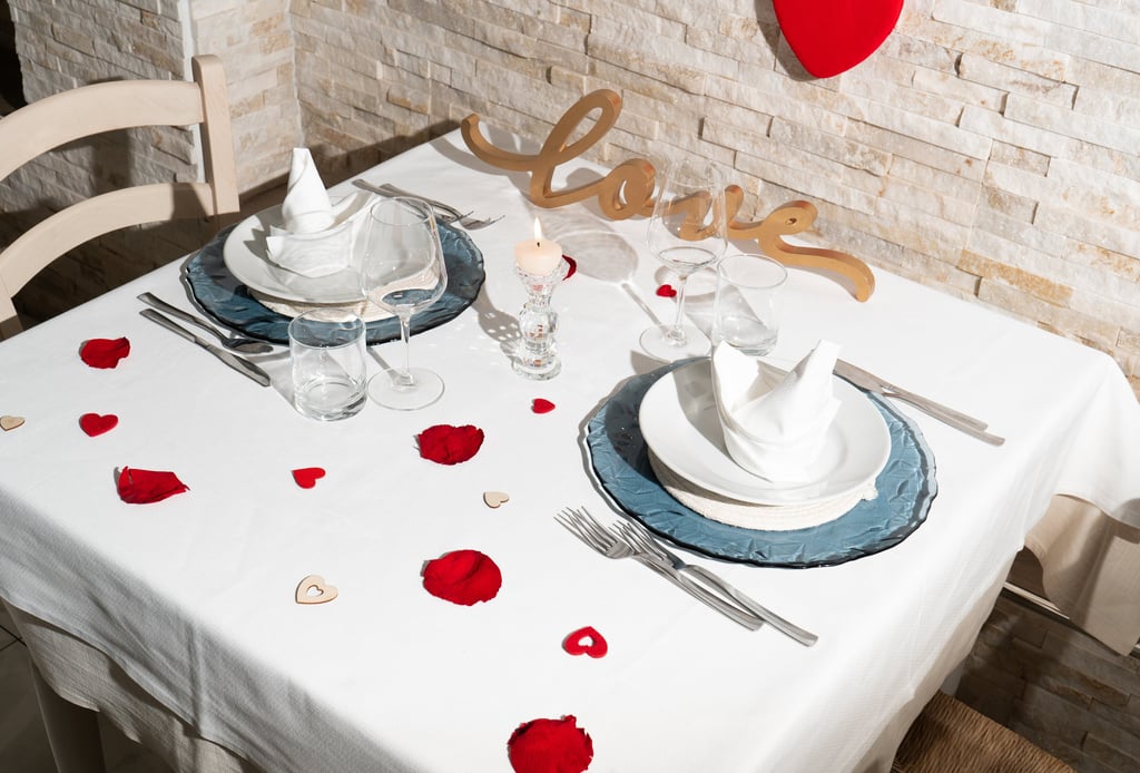 tavolo di ristorante elegantemente e romanticamente apparecchiato con petali di rose