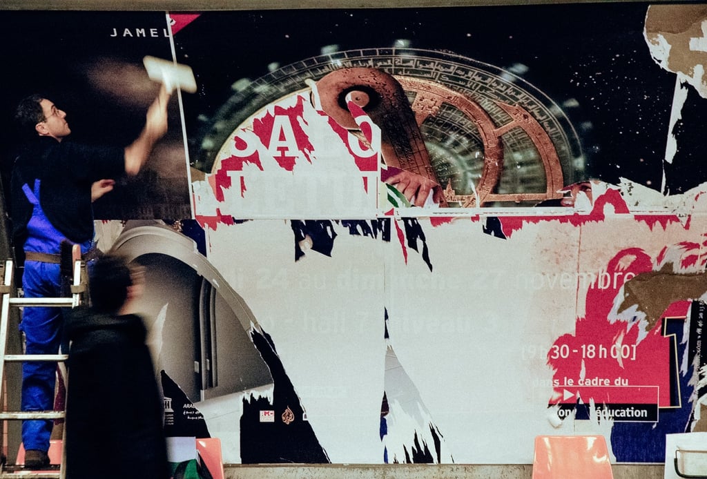 Man plastering posters in Montparnasse-Bienvenüe station in Paris