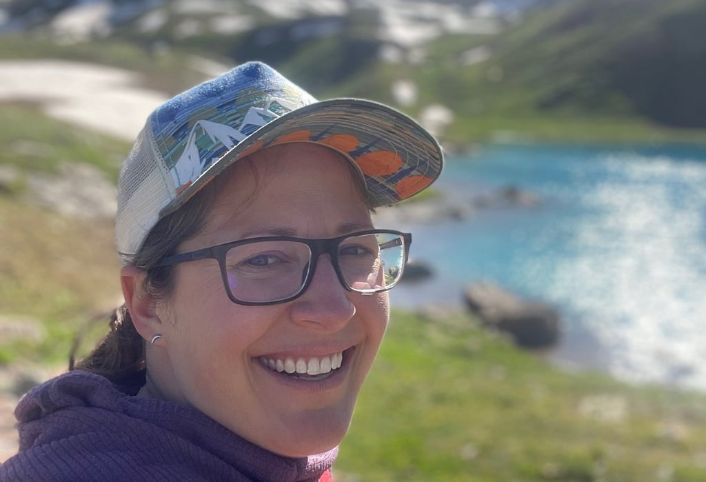 Jenna Smiling Outside in a hat by a lake