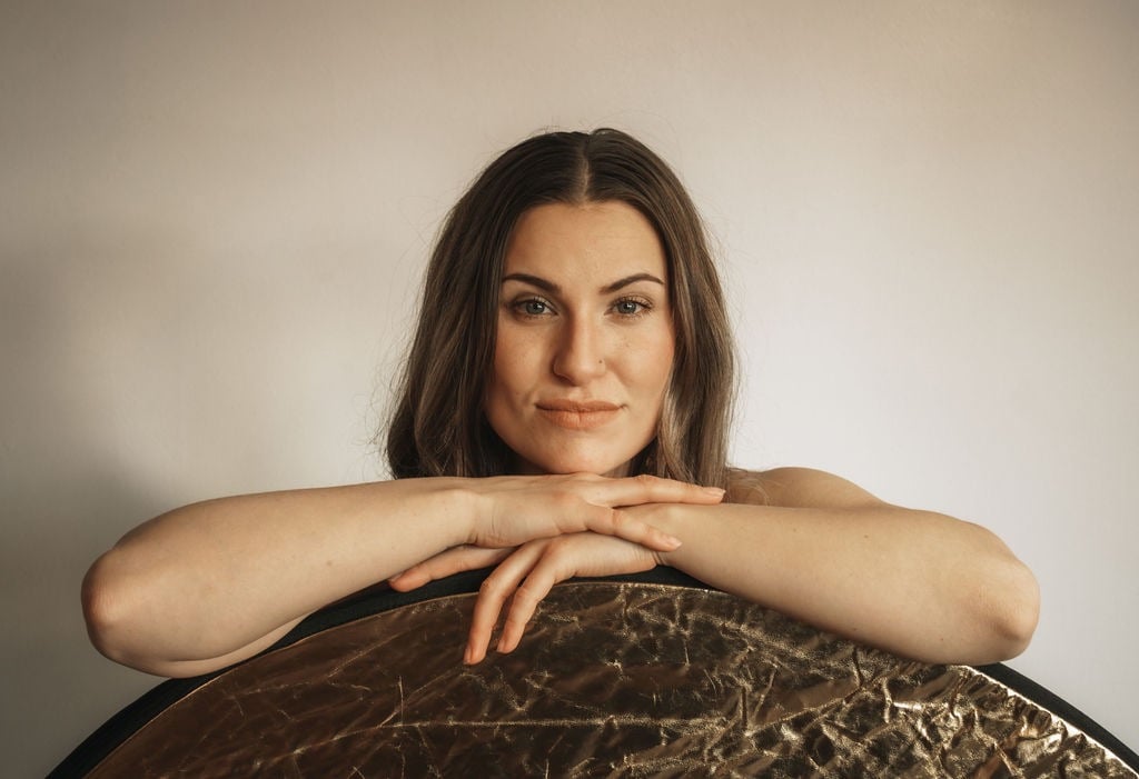 a woman resting her chin on her hands, her arms are resting on an object