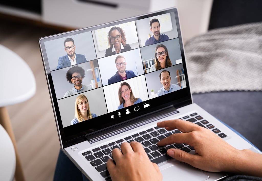 A person with a laptop participating in a virtual team meeting