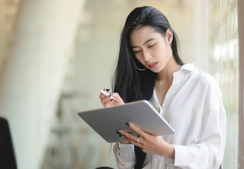 A young businesswoman using a digital tablet while standing in a modern office.